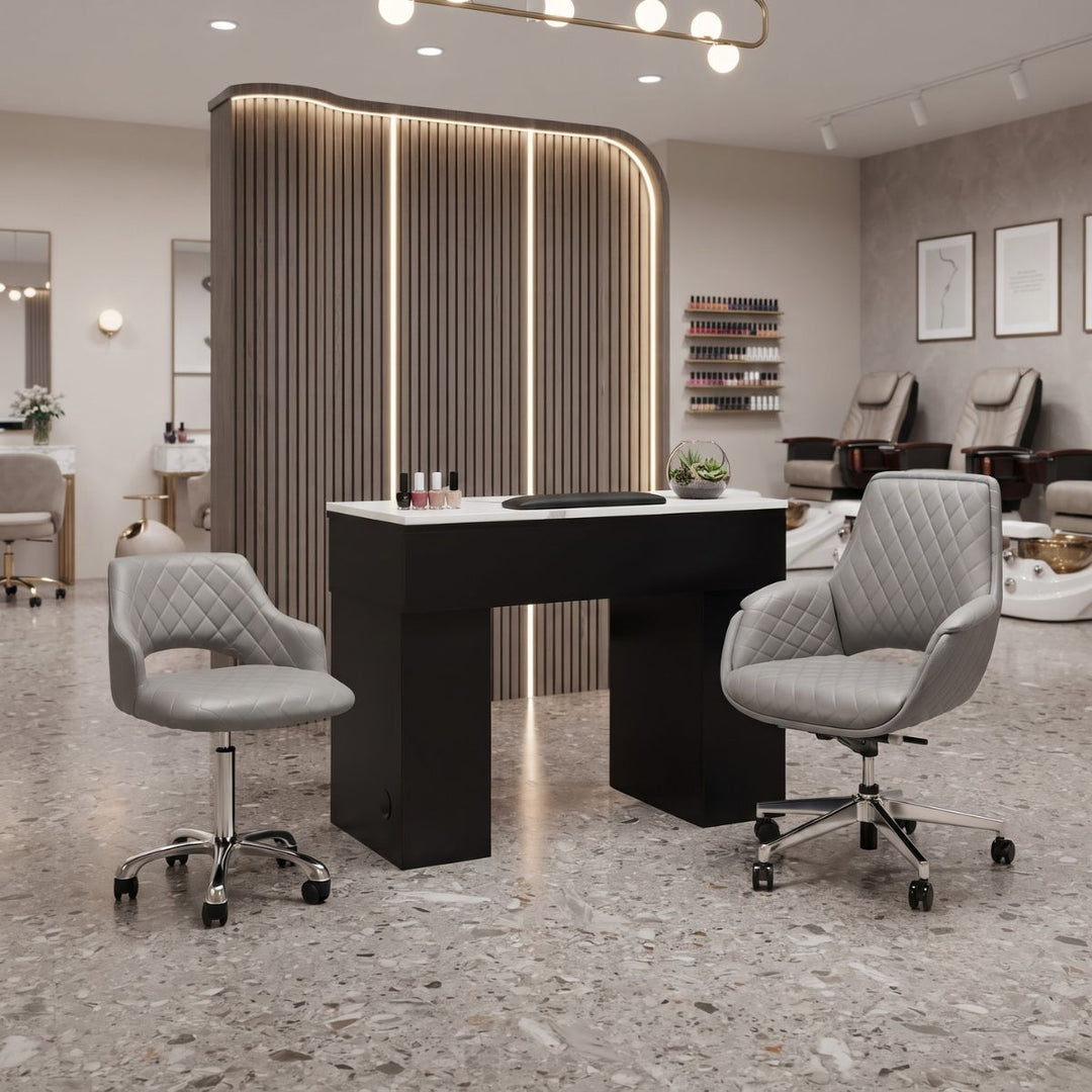 Black manicure station with white top and grey quilted swivel chairs in a modern salon setup.